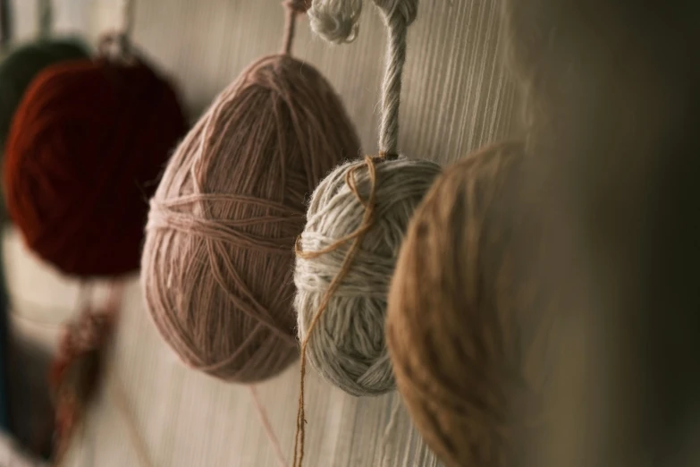 a bunch of balls of yarn hanging on a wall, unsplash, arts and crafts movement, close - up photograph, eggs, low colour, shot on sony a 7
