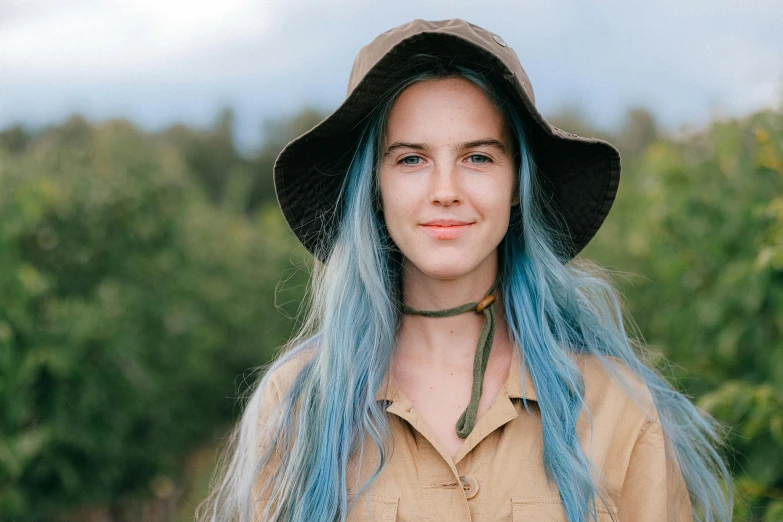 a woman with blue hair wearing a hat, inspired by Louisa Matthíasdóttir, pexels contest winner, wearing farm clothes, brunette with dyed blonde hair, high forehead, “ iron bark