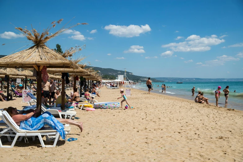 a group of people sitting on top of a sandy beach, parasols, meni chatzipanagiotou, travel guide, square