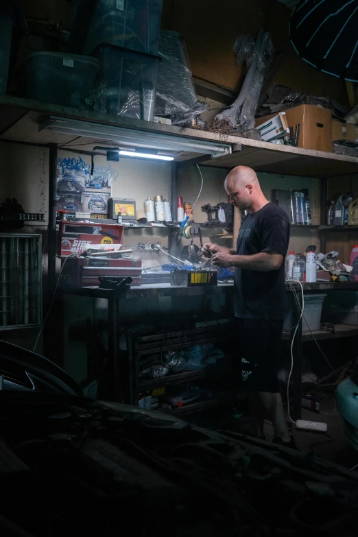 a man that is standing in a garage, assemblage, extremely good lighting, aftermarket parts, production photo, working