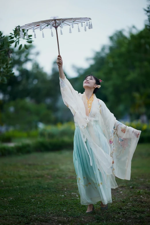 a woman standing in a field holding an umbrella, inspired by Lan Ying, wearing authentic attire, waving, trending photo, robe