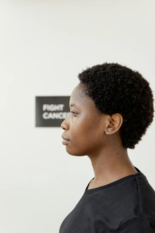 a woman standing in front of a white wall, inspired by Carrie Mae Weems, face profile, boy has short black hair, looking frontal view, stood in a lab