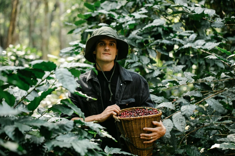 a man in a hat holding a basket of coffee beans, amongst foliage, lachlan bailey, yan gisuka, profile image