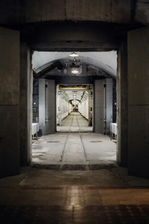 a long hallway with a clock on the wall, inspired by Thomas Struth, unsplash, bauhaus, underground mine, military base, gray, stockholm