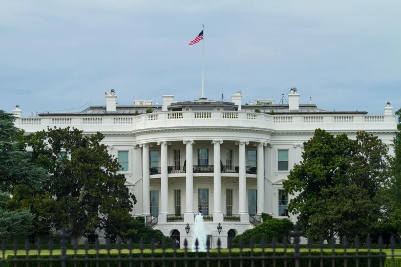 a large white building with a flag on top of it, by Samuel Washington Weis, pexels contest winner, obama, view from front, preserved historical, 🚿🗝📝