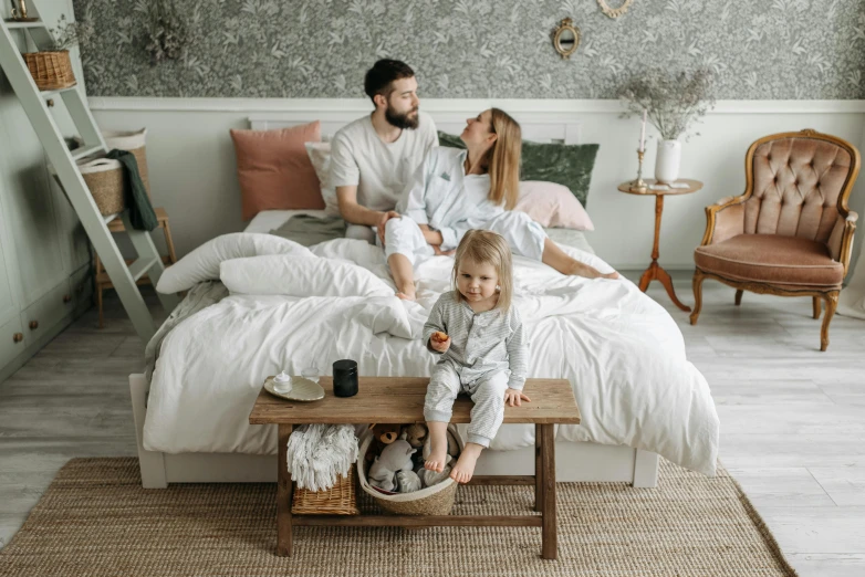 a man and woman sitting on a bed with a child, by Adam Marczyński, pexels contest winner, renaissance, 15081959 21121991 01012000 4k, white furniture, cozy wallpaper, ultra high quality model