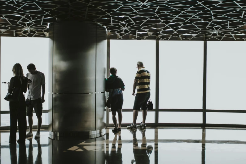 a group of people standing in front of a window, pexels contest winner, visual art, auckland sky tower, standing in a large empty hall, group of people in an elevator, three views