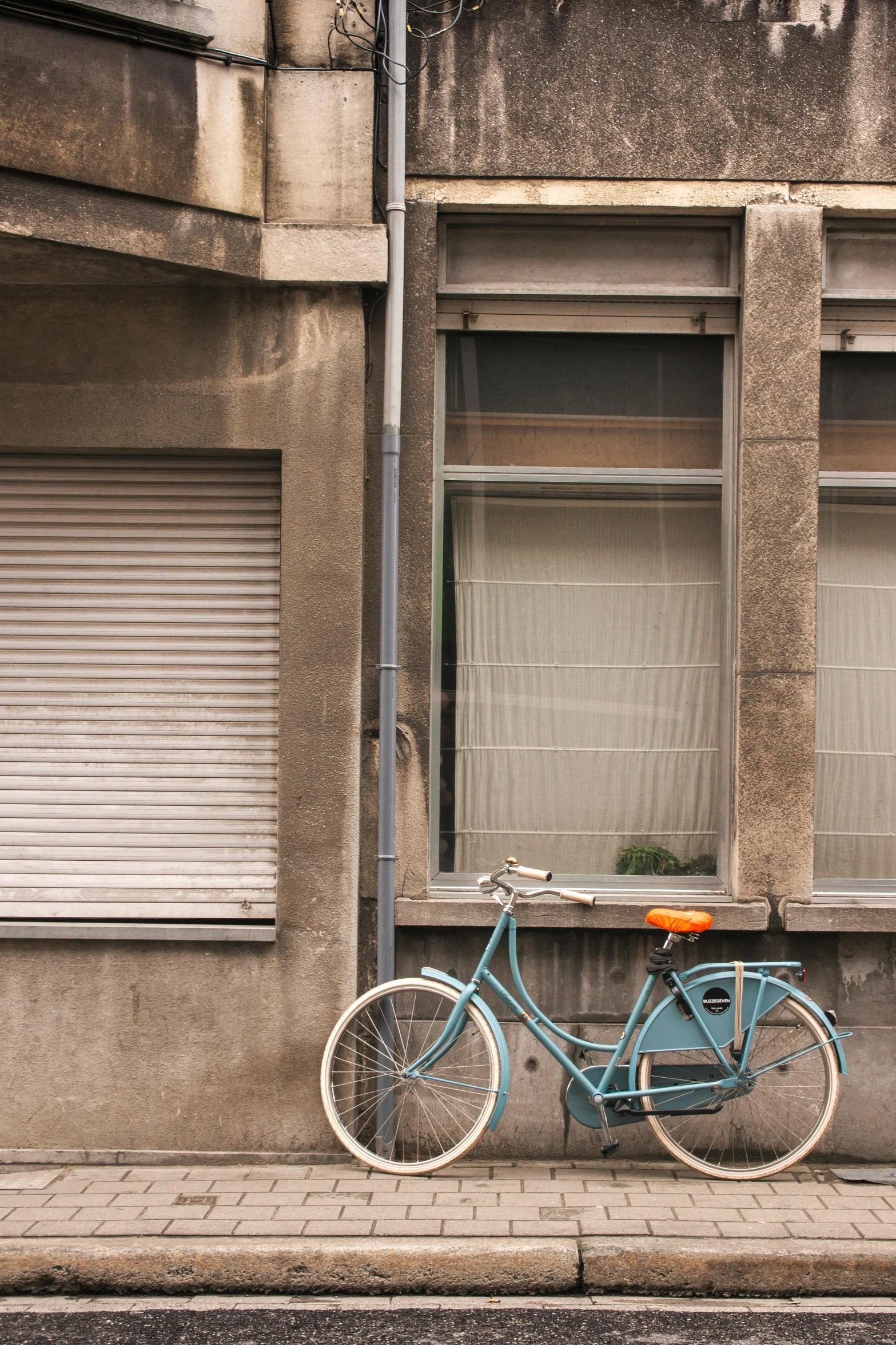 a blue bicycle parked in front of a building, shutter, teal orange, grey, colour photograph