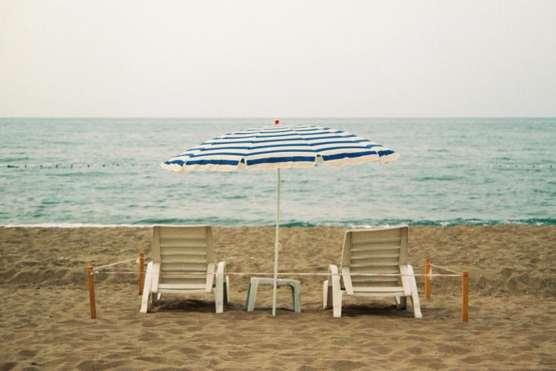 two lawn chairs and an umbrella on a beach, unsplash, minimalism, italian masterpiece, instagram photo, striped, calm seas
