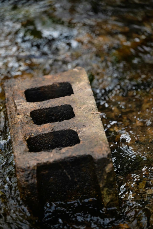 a brick that is sitting in some water, inspired by Hubert Robert, unsplash, land art, metal towers and sewers, rule of three, creek, close up image