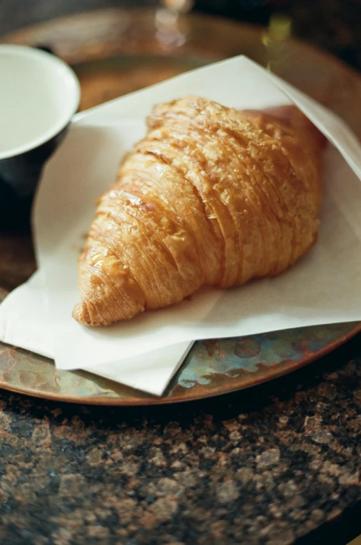 a plate topped with a croissant next to a cup of coffee, renaissance, award-winning crisp details”, fan favorite, award - winning crisp details ”, parchment paper