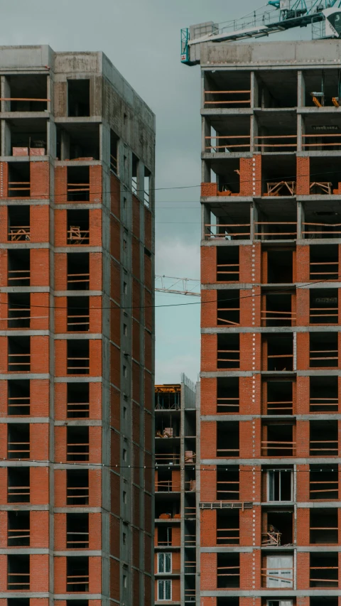 a couple of tall buildings sitting next to each other, by Attila Meszlenyi, pexels contest winner, constructivism, under construction, cinematic establishing shot, red bricks, gif