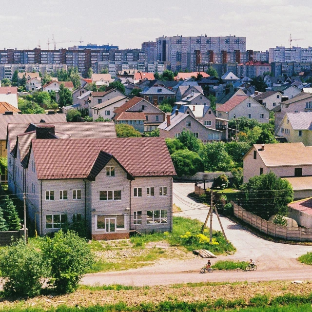 a group of houses sitting on top of a lush green hillside, an album cover, by Attila Meszlenyi, unsplash, socialist realism, russian orbit city cityscape, 000 — википедия, 1990s photograph, panoramic