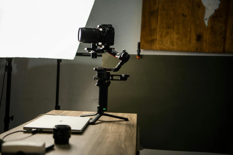 a camera sitting on top of a wooden table, pointing at the camera, soft volumetric lighting, a still of an ethereal, production ig studios