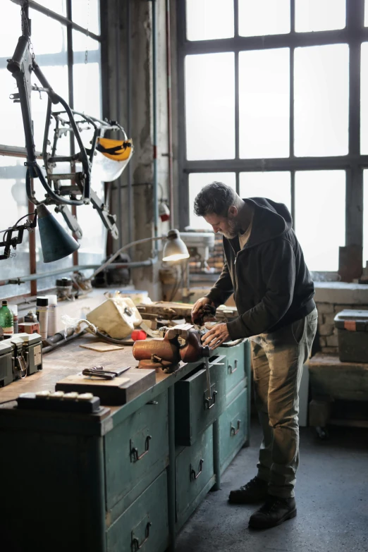 a man working on a piece of wood in a workshop, a picture, by Jan Tengnagel, arbeitsrat für kunst, made from mechanical parts, production photo