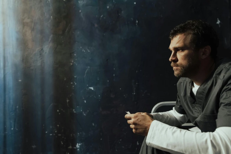 a man sitting in a chair smoking a cigarette, a portrait, unsplash, with prison clothing, herry cavill, profile image, h3h3