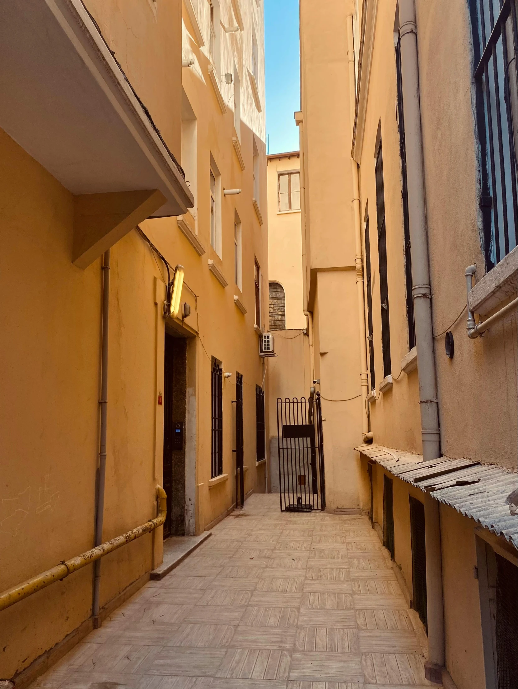 a narrow alley with a bench in between two buildings, yellow walls, low quality photograph, cannes, profile image