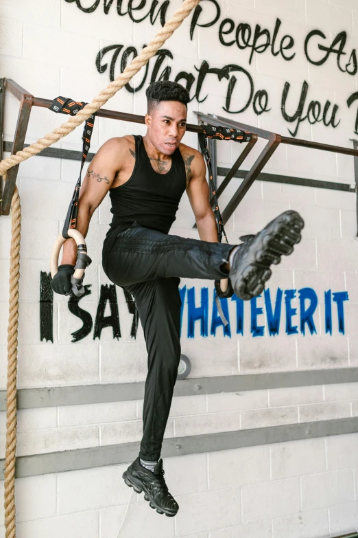 a man hanging from a rope in a gym, inspired by Randy Vargas, happening, non binary model, wearing tall combat boots, profile image, promotional image