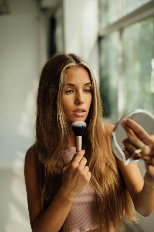 a woman brushing her hair in front of a mirror, trending on pexels, sexy face with full makeup, slightly tanned, powder, influencer