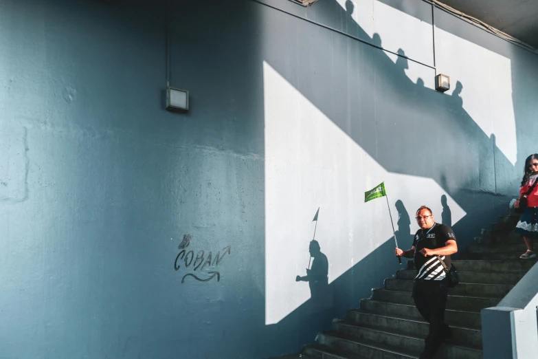 a couple of people that are standing on some stairs, a photo, unsplash contest winner, street art, green flag, high shadow, football hooligans, sofya emelenko