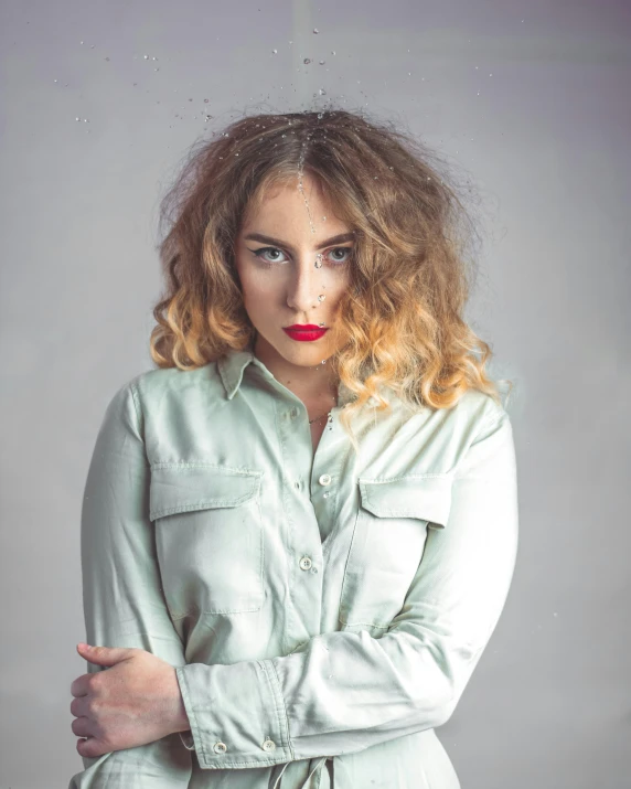 a woman in a green shirt posing for a picture, an album cover, inspired by Elsa Bleda, trending on pexels, bushy grey eyebrows, attractive androgynous humanoid, curls and curves, frowning