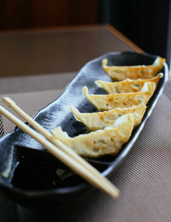 a close up of a plate of food with chopsticks, in the evening