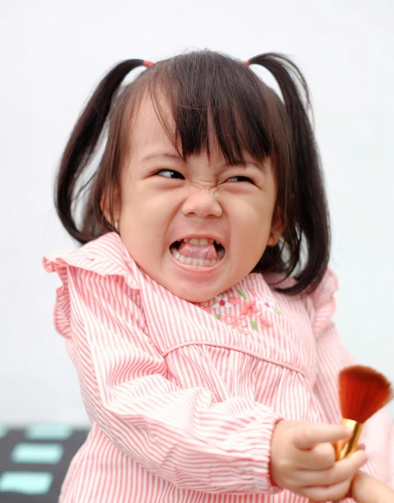 a little girl holding a wooden spoon in her hands, an album cover, inspired by Tooth Wu, pexels contest winner, mingei, very angry expression, grinning lasciviously, young asian girl, the angry