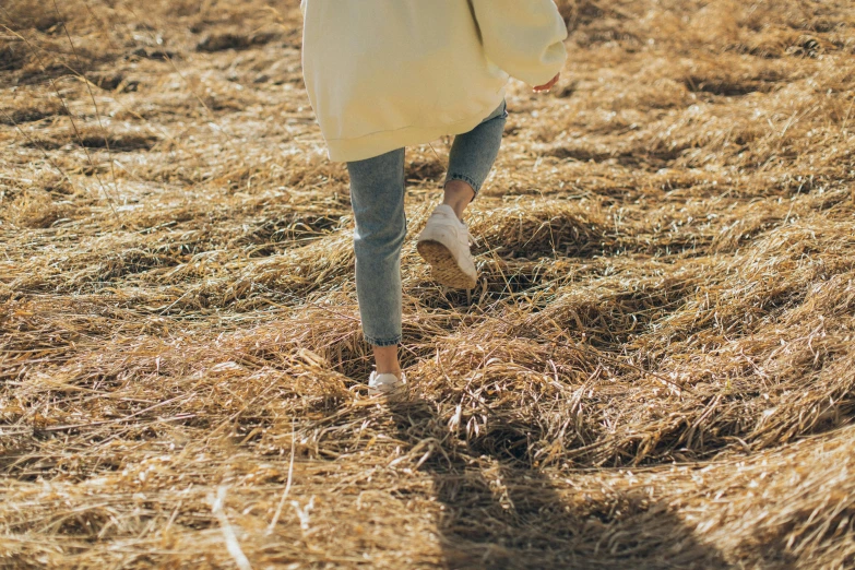 a woman walking through a field holding an umbrella, trending on pexels, wearing hay coat, wearing white sneakers, avatar image, wearing jeans