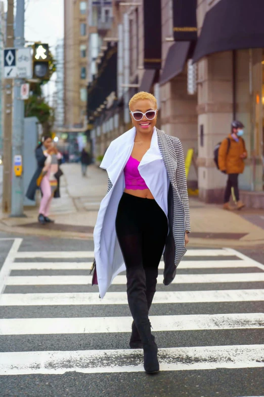 a woman walking across a crosswalk on a city street, an album cover, trending on pexels, happening, nicki minaj curvy, humans of new york style, woman with rose tinted glasses, physical : tinyest midriff ever