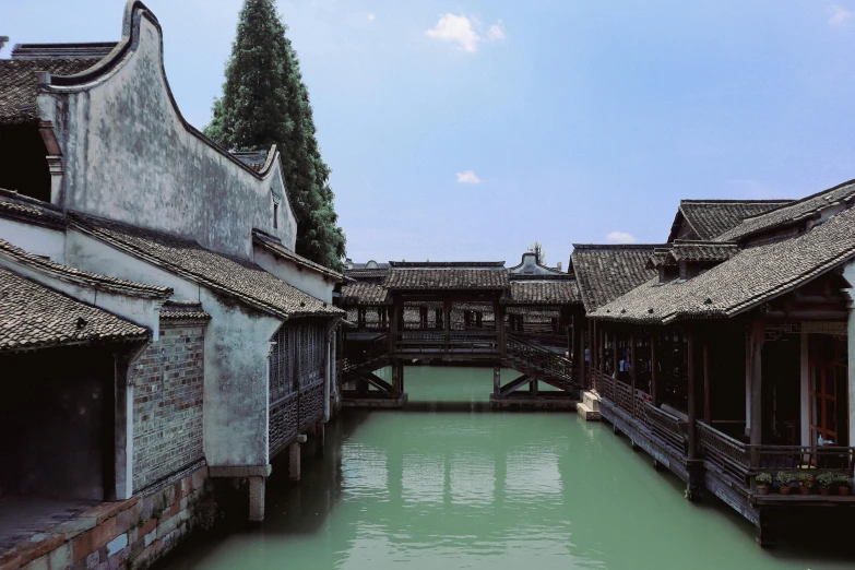 a group of buildings sitting next to a body of water, an album cover, inspired by Gu An, pexels contest winner, mingei, old bridge, 4 k photo autochrome, chinese architecture, feng zhu |