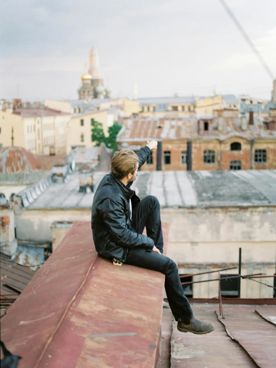 a man sitting on the roof of a building, an album cover, inspired by Alexey Venetsianov, pexels contest winner, low quality photo, russian city, bo burnham, chill time. good view