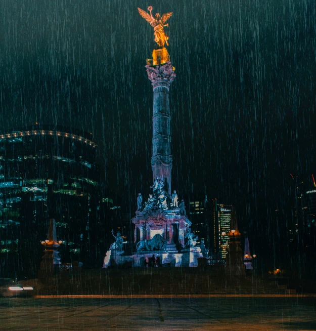 a statue in the middle of a city at night, by Alejandro Obregón, pexels contest winner, realism, pixelated rain, mexico city, holiday season, water tornado in the city