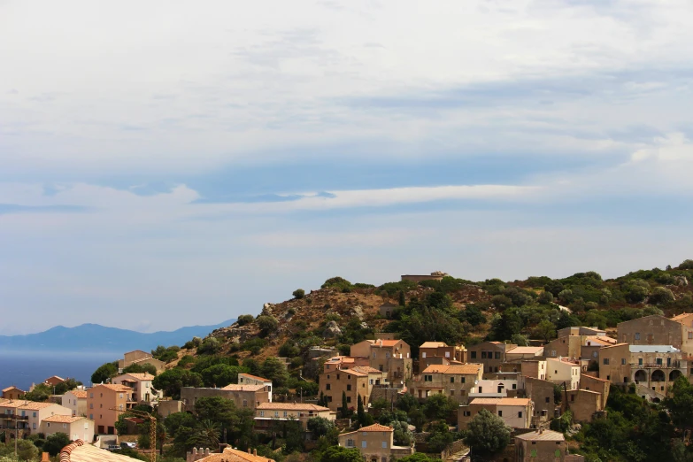 a group of buildings sitting on top of a lush green hillside, by Alexis Grimou, les nabis, traditional corsican, slide show, skies, grey