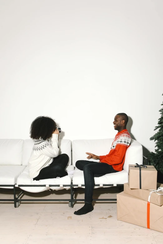 a man and a woman sitting on a couch in front of a christmas tree, virgil abloh, man sitting facing away, npc talking, man proposing his girlfriend