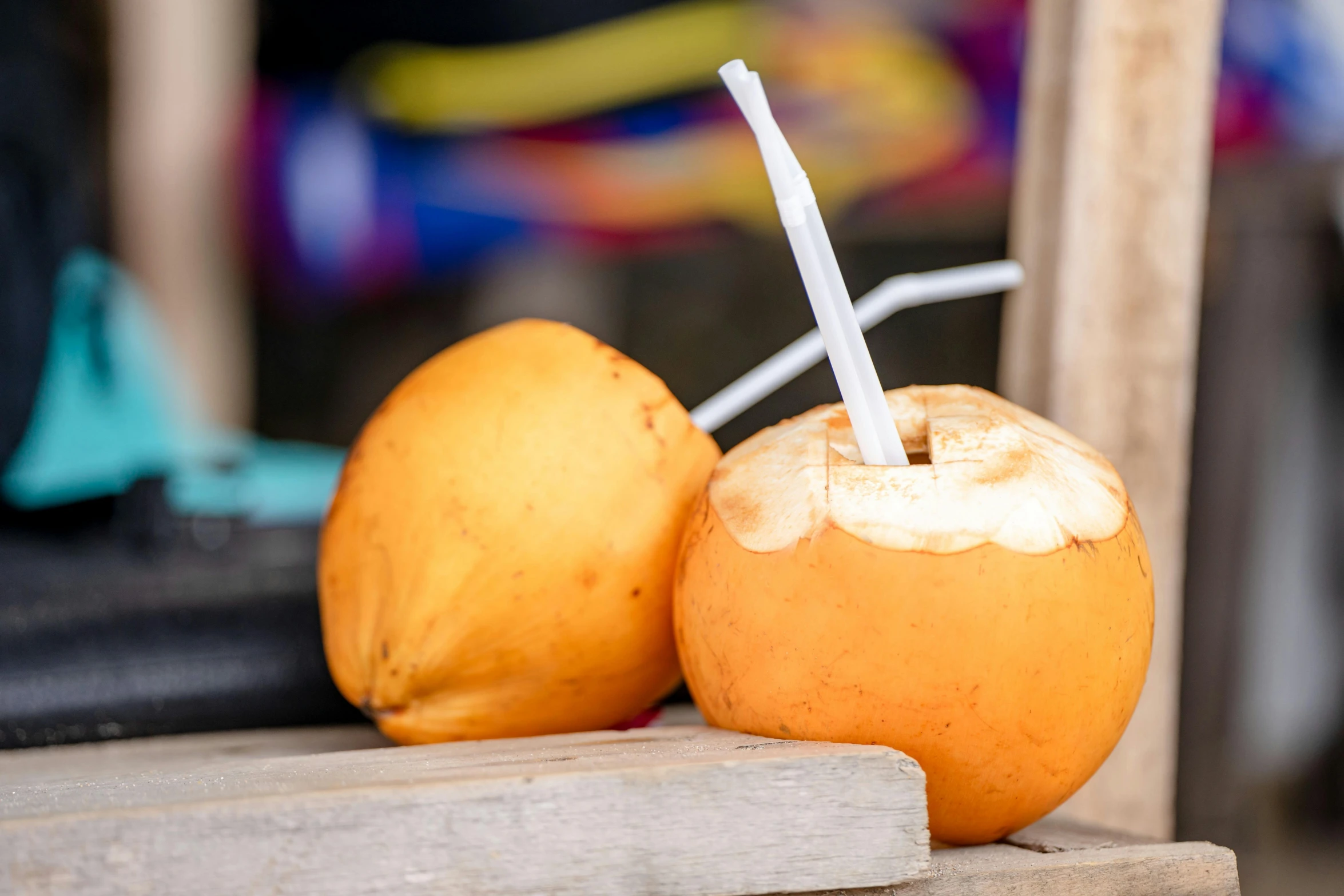 a couple of oranges sitting on top of a wooden table, with a straw, coconuts, profile image, food stall