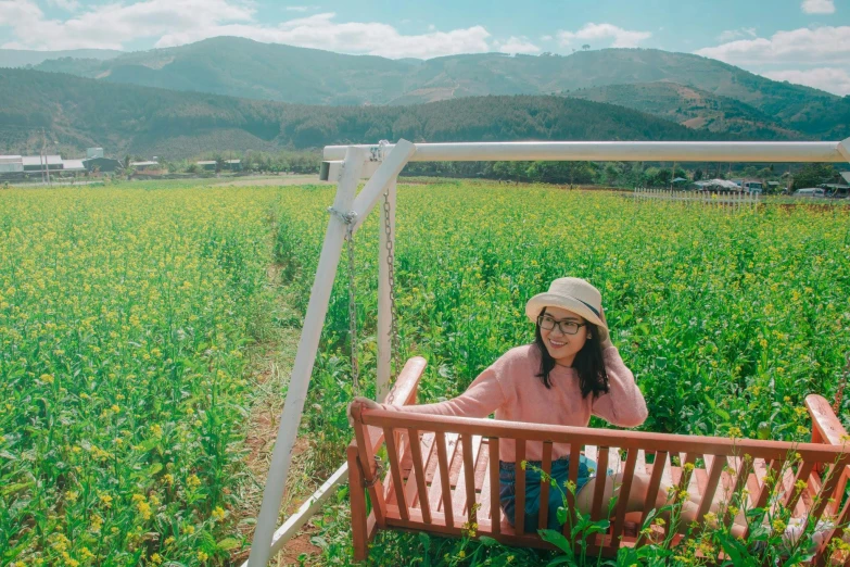 a woman sitting on a bench in a field, pexels contest winner, sumatraism, avatar image, background image, idyllic and fruitful land, patiphan sottiwilaiphong