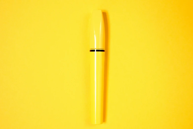 a yellow pen sitting on top of a yellow surface, heavy mascara, in a luminist style, but minimalist, simple primitive tube shape
