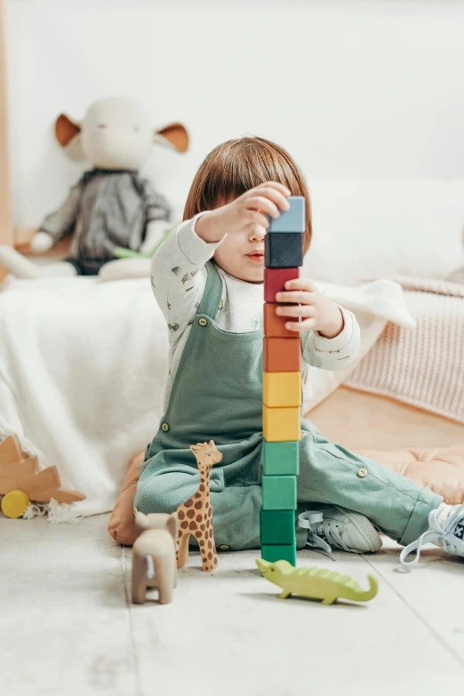 a little girl sitting on the floor playing with wooden blocks, pexels contest winner, towering above a small person, pastel', scientific, instagram post