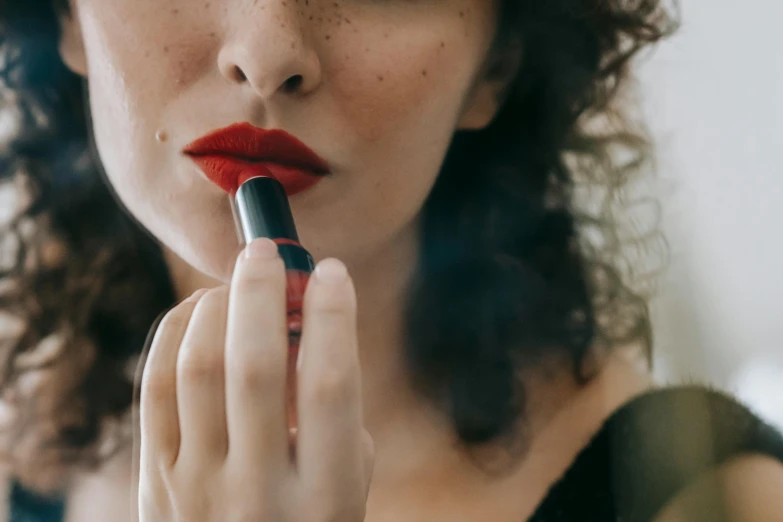 a woman putting on lipstick in front of a mirror, inspired by Man Ray, trending on pexels, photorealism, red and black, with freckles, vibrent red lipstick, sephora