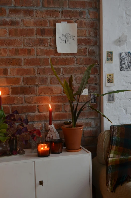 a chair sitting in a living room next to a brick wall, by Else Alfelt, reddit, light and space, candles!, houseplant, our art corner, profile image