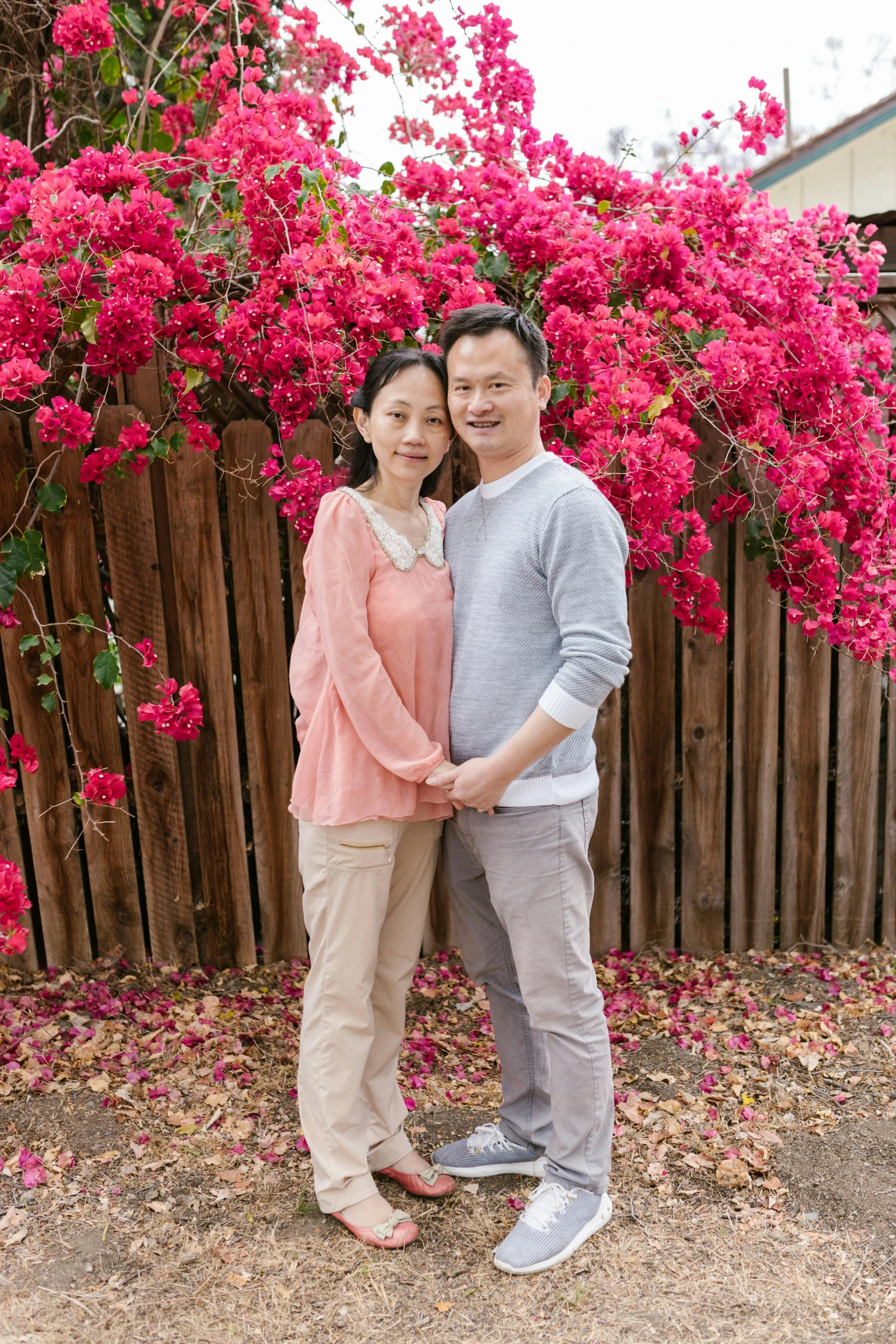 a man and a woman standing next to each other, a picture, inspired by Chen Chun, bougainvillea, family photography, avatar image, casual clothing