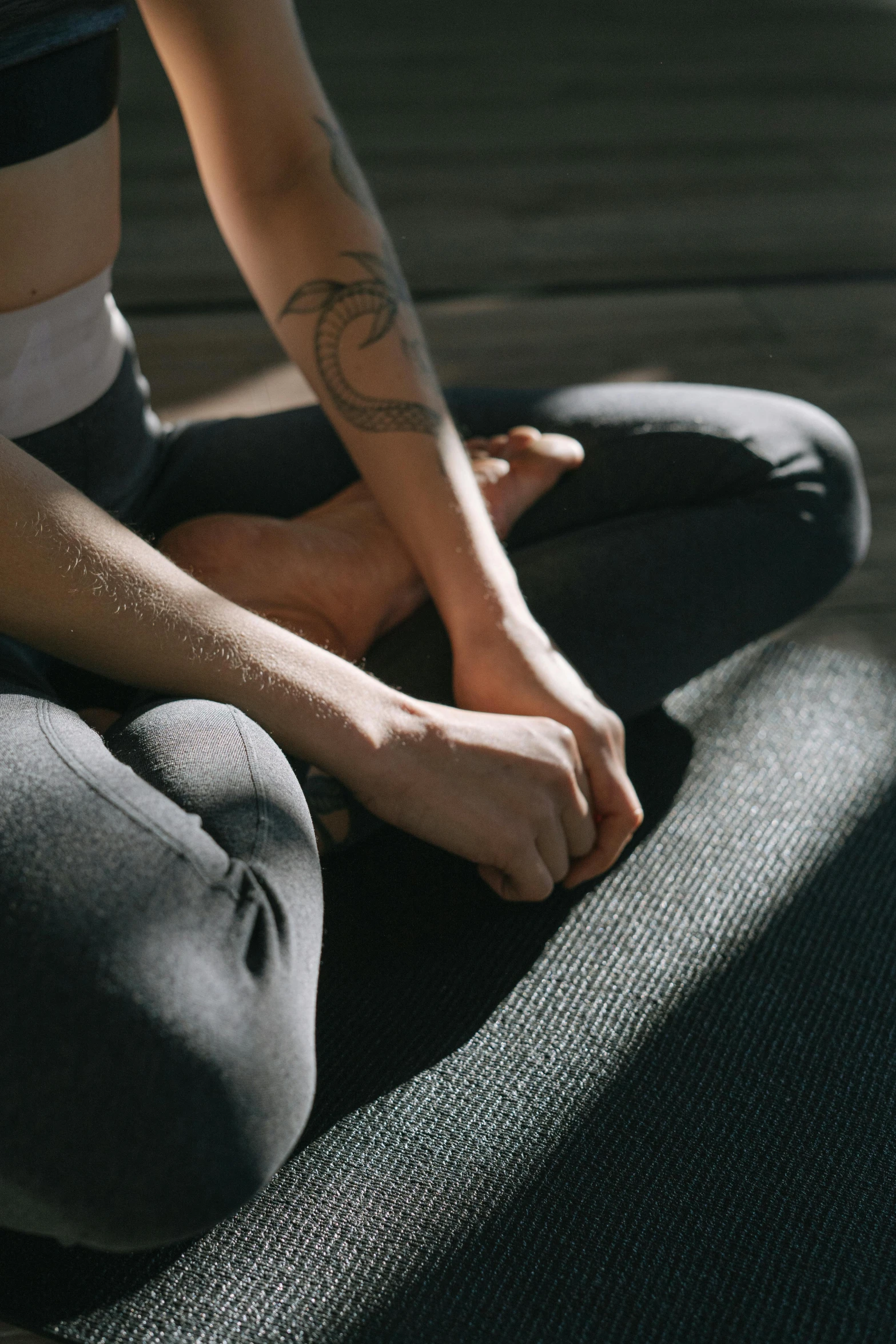 a woman sitting on top of a yoga mat, a tattoo, inspired by Elsa Bleda, trending on pexels, renaissance, grey, gesture, low quality photo, dark warm light