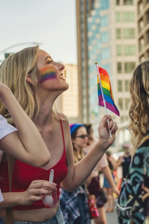 a group of women standing next to each other on a street, a photo, by Julia Pishtar, shutterstock, pride parade, profile image, blonde, flag in hands