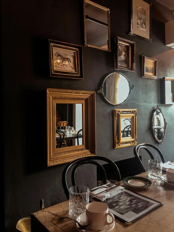 a dining room with a wooden table and chairs, a portrait, by Jan Tengnagel, trending on unsplash, renaissance, black and gold rich color, very smoky paris bar, picture frames, in chippendale sydney