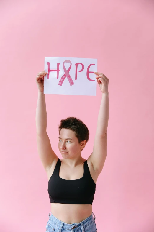 a woman holding up a sign that says hope, pexels contest winner, pink body, white ribbon, cait miers, hgh