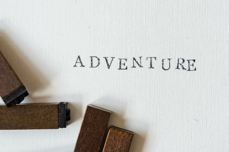 a couple of stamps sitting on top of a piece of paper, inspired by Salomon van Abbé, pexels contest winner, expectation of adventure, lettering, wooden jewerly, action - adventure