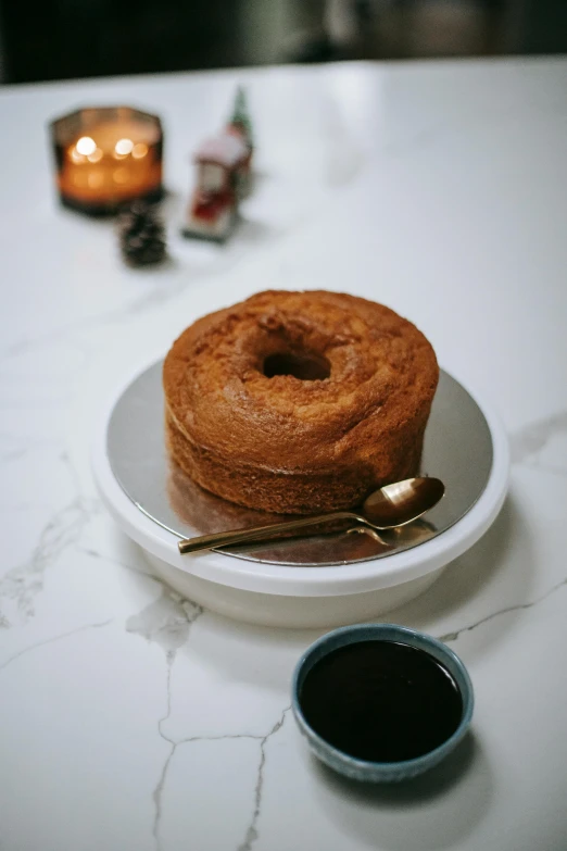 a white plate topped with a donut next to a cup of coffee, by Winona Nelson, unsplash, baroque, with a bundt bundt pan face, wine, cane, huge black round hole