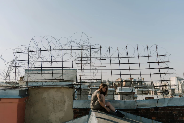 a man sitting on the roof of a building, inspired by Elsa Bleda, pexels contest winner, graffiti, barbed wire, anastasia ovchinnikova, an young urban explorer woman, ignant