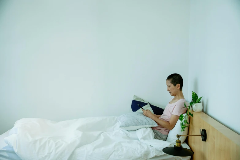 a woman sitting on a bed reading a book, happening, profile image, dwell, fully functional, white bed