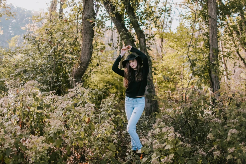 a woman standing in the middle of a forest, a picture, by Emma Andijewska, unsplash, visual art, black jeans, doing a sassy pose, with soft bushes, 😭 🤮 💕 🎀